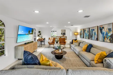 a living room with furniture kitchen view and a large window