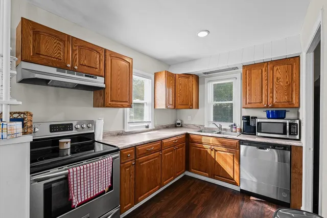 a kitchen with stainless steel appliances granite countertop wooden floors a stove a sink a dining table and chairs