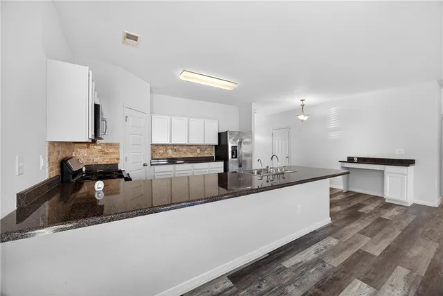 a large white kitchen with cabinets a sink and a stove