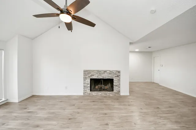 an empty room with fan and fireplace