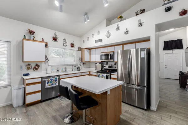 a kitchen with stainless steel appliances a sink a stove a refrigerator cabinets and wooden floor