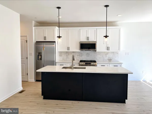 a kitchen with stainless steel appliances kitchen island a sink refrigerator and cabinets