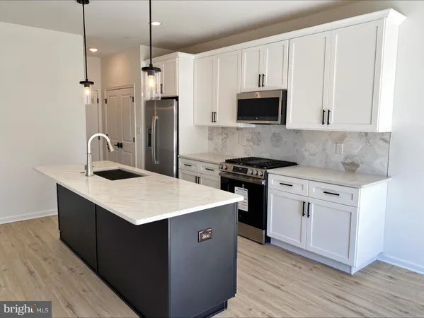 a kitchen with stainless steel appliances granite countertop a sink stove a refrigerator and white cabinets with wooden floor