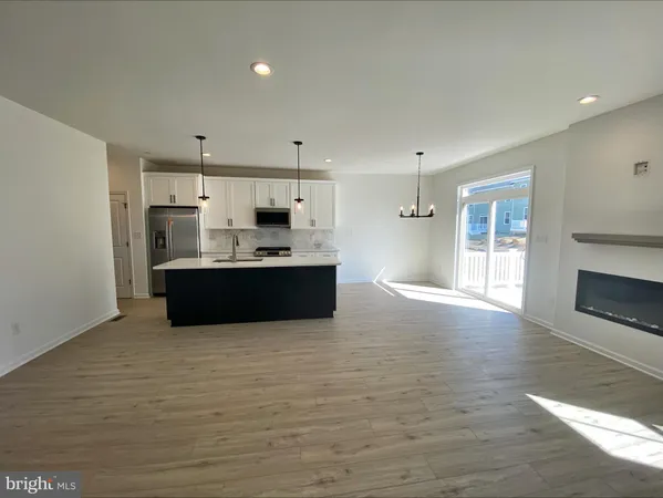 a view of kitchen with kitchen island stainless steel appliances a sink cabinets and wooden floor