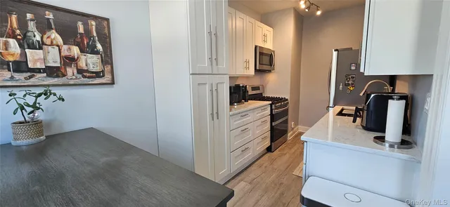 a view of a kitchen with fridge and wooden floor