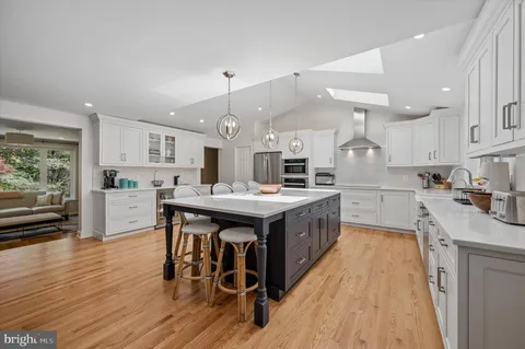 a kitchen with stainless steel appliances kitchen island granite countertop a table chairs sink and cabinets