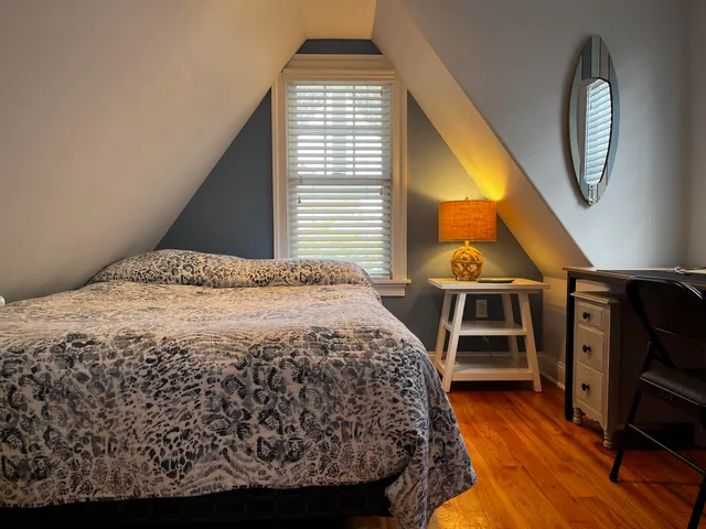 a bedroom with a bed a dresser and wooden floor