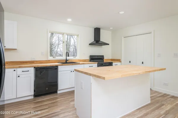 a kitchen with stainless steel appliances white cabinets and wooden floor