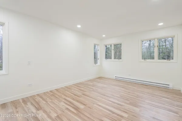 an empty room with wooden floor and windows
