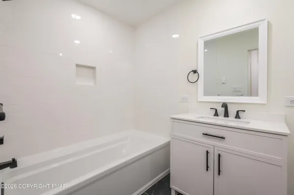 a bathroom with a bathtub sink vanity and mirror