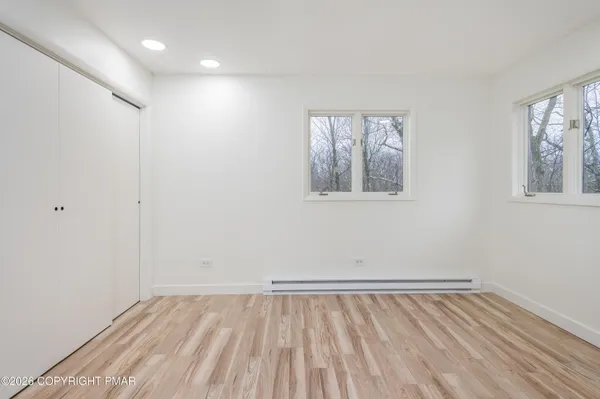 a view of an empty room with wooden floor and a window
