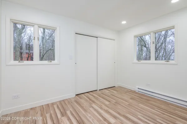 a view of empty room with wooden floor and fan