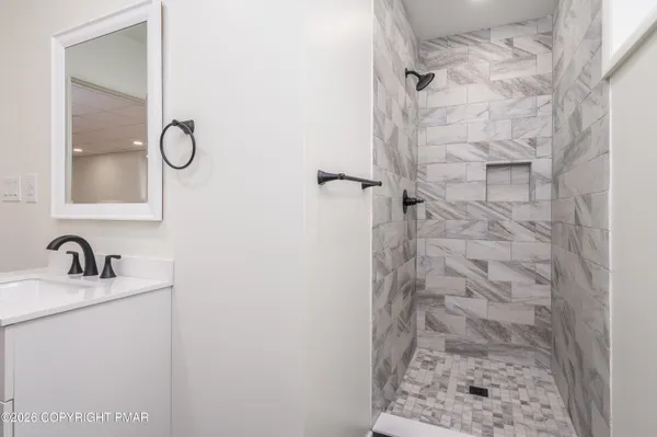 a bathroom with a granite countertop shower sink and mirror