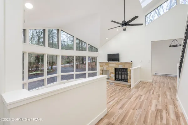 a view of a livingroom with a fireplace a ceiling fan and wooden floor