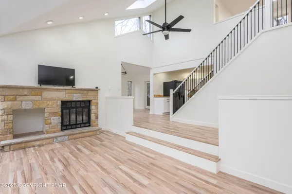 a view of a livingroom with an empty kitchen and a fireplace