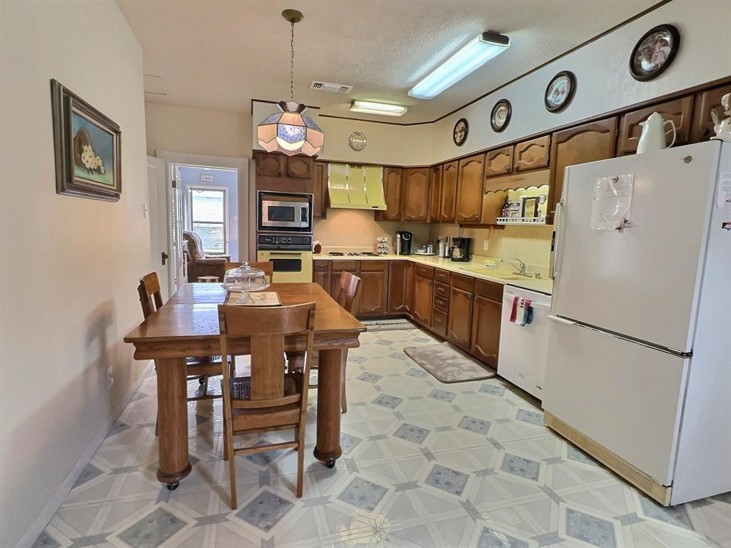 300 South Miller Street Rising Star, TX 76471 - Photo 14 of 39 a kitchen with stainless steel appliances granite countertop a refrigerator a sink dishwasher a dining table and chairs with wooden floor