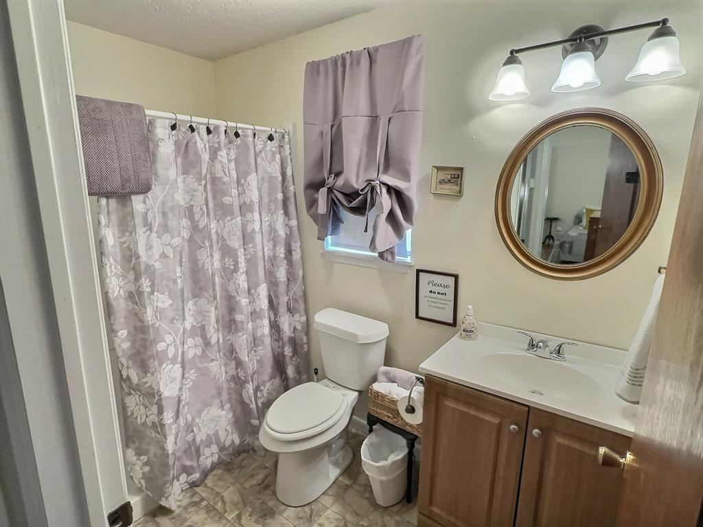 300 South Miller Street Rising Star, TX 76471 - Photo 23 of 39 a bathroom with a toilet a sink and a mirror