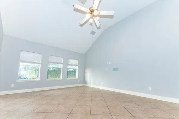 an empty room with windows and ceiling fan
