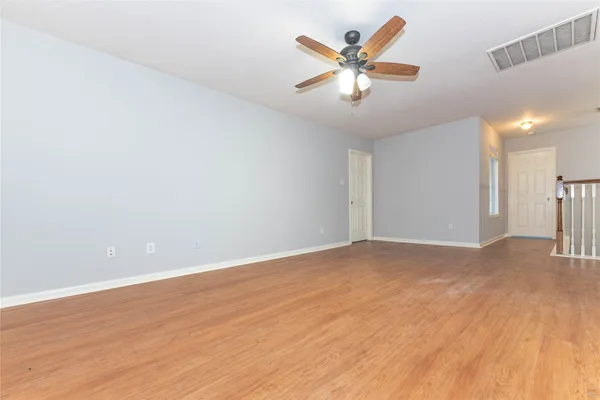 a view of a room with wooden floor and a ceiling fan