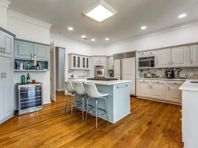 a kitchen with kitchen island stainless steel appliances a stove a sink a refrigerator cabinets and a dining table