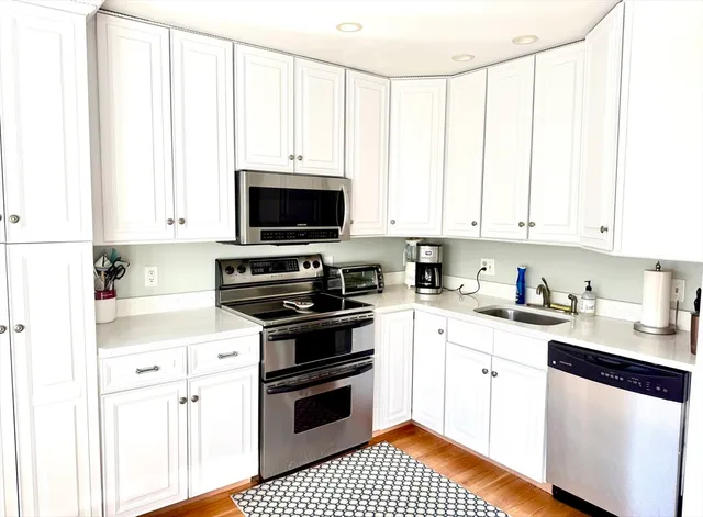 a kitchen with stainless steel appliances white cabinets and a stove top oven
