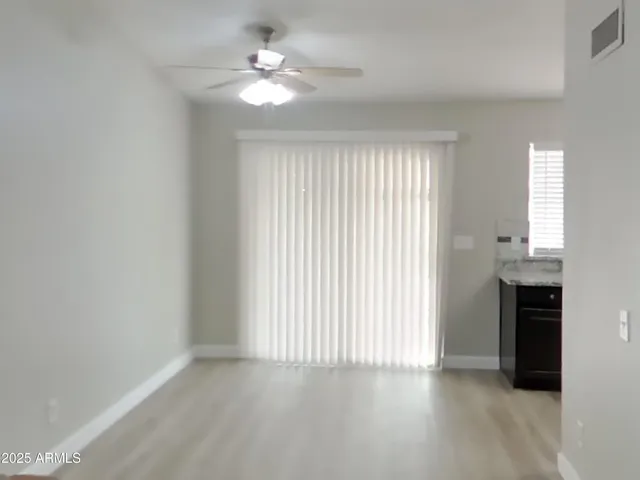 an empty room with windows and chandelier fan