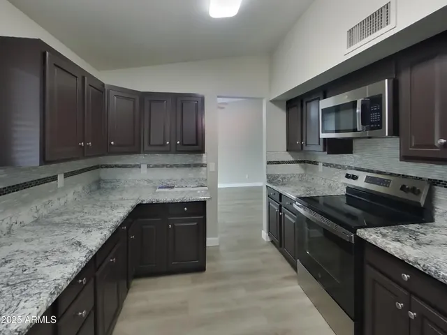 a kitchen with granite countertop stainless steel appliances and wooden cabinets