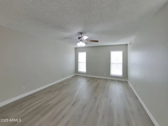 a view of an empty room with wooden floor and window
