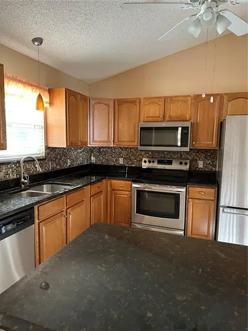 a kitchen with granite countertop a refrigerator and a sink