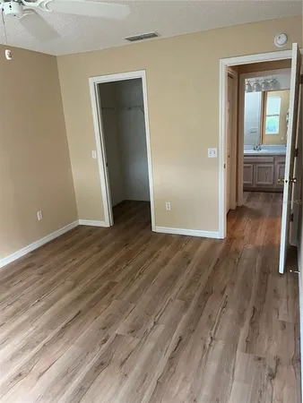 an empty room with wooden floor fan and windows