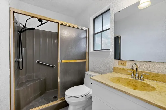 a bathroom with a granite countertop sink toilet and shower