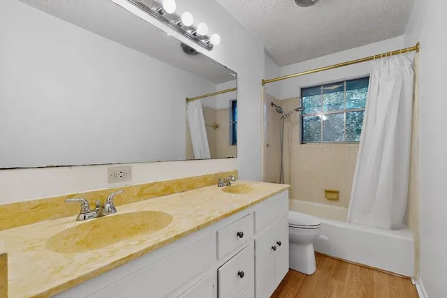 a bathroom with a granite countertop sink a toilet and bathtub