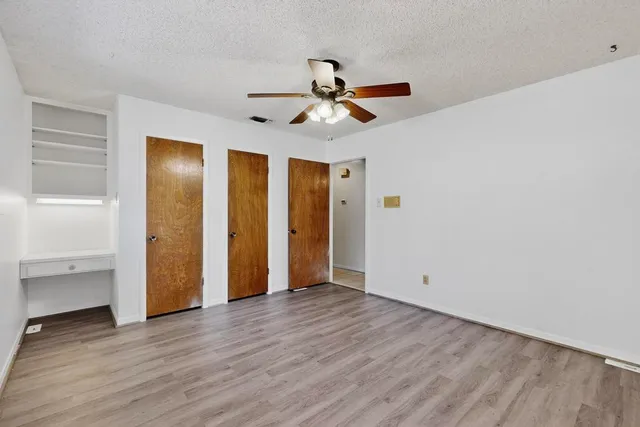 an empty room with wooden floor a ceiling fan and entryway