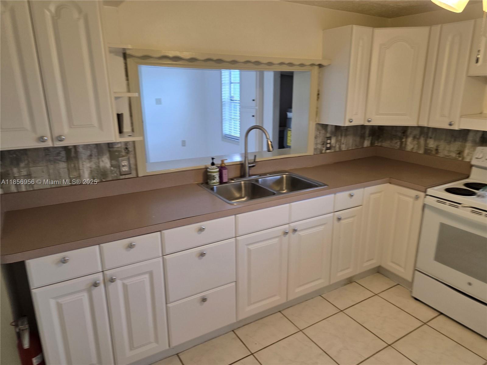 a kitchen with white cabinets and sink