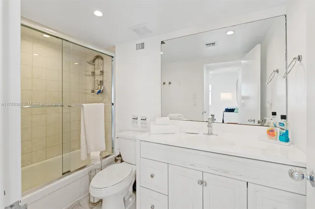 a bathroom with a shower sink vanity mirror and toilet