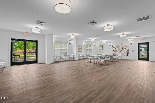 an empty room with chandelier fan and windows