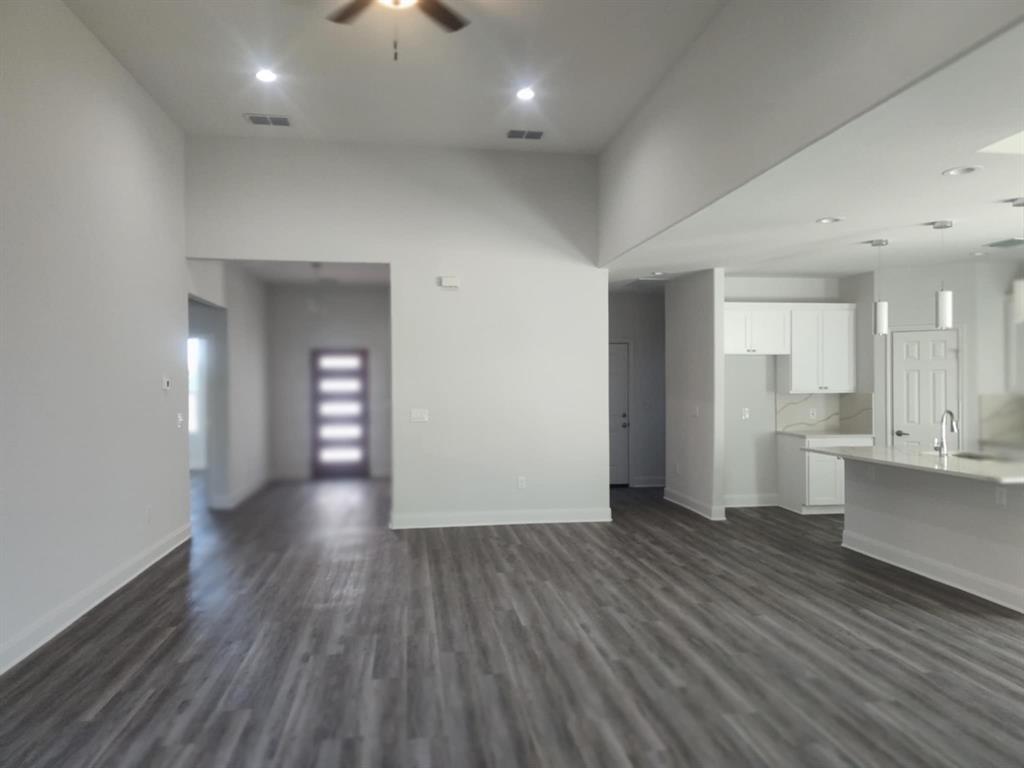 20008 Boggy Ford Road Lago Vista, TX 78645 - Photo 5 of 17 Unfurnished living room with a ceiling fan, dark wood-style flooring, recessed lighting, and a towering ceiling