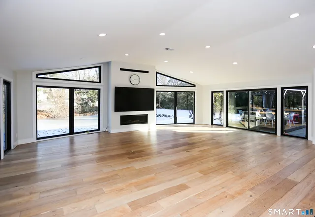 a view of an empty room with wooden floor and windows