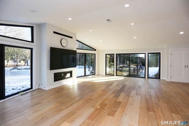 a view of an empty room with wooden floor and windows