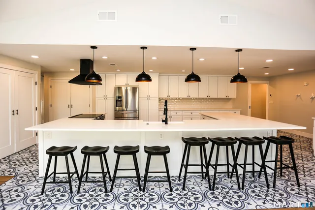 a kitchen with stainless steel appliances kitchen island granite countertop a dining table chairs and white cabinets