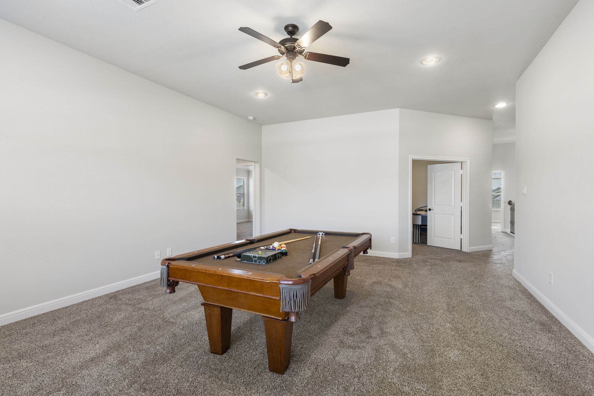 2819 Bradbury Hills Road Spring, TX 77373 - Photo 40 of 50 Spacious recreational room with a pool table, neutral carpeting, and a ceiling fan. It features ample lighting and access to adjacent rooms, creating an inviting entertainment space.