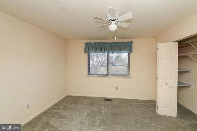 an empty room with a ceiling fan and a window