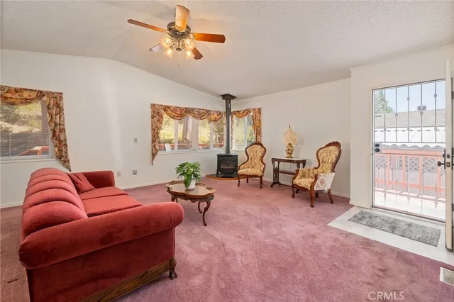 a living room with furniture a chandelier fan and a large window
