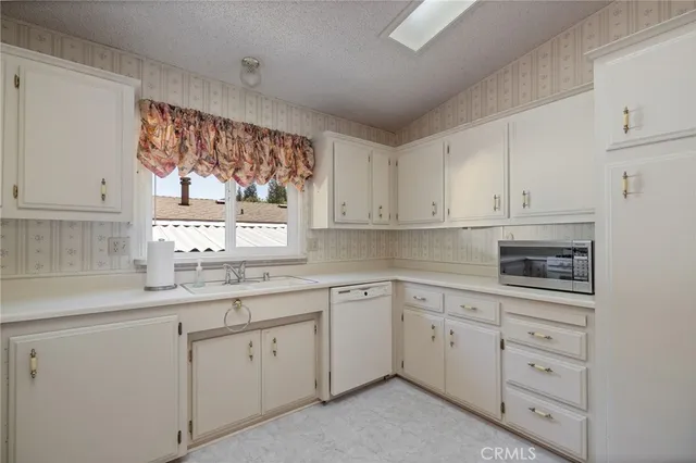 a kitchen with white cabinets and window