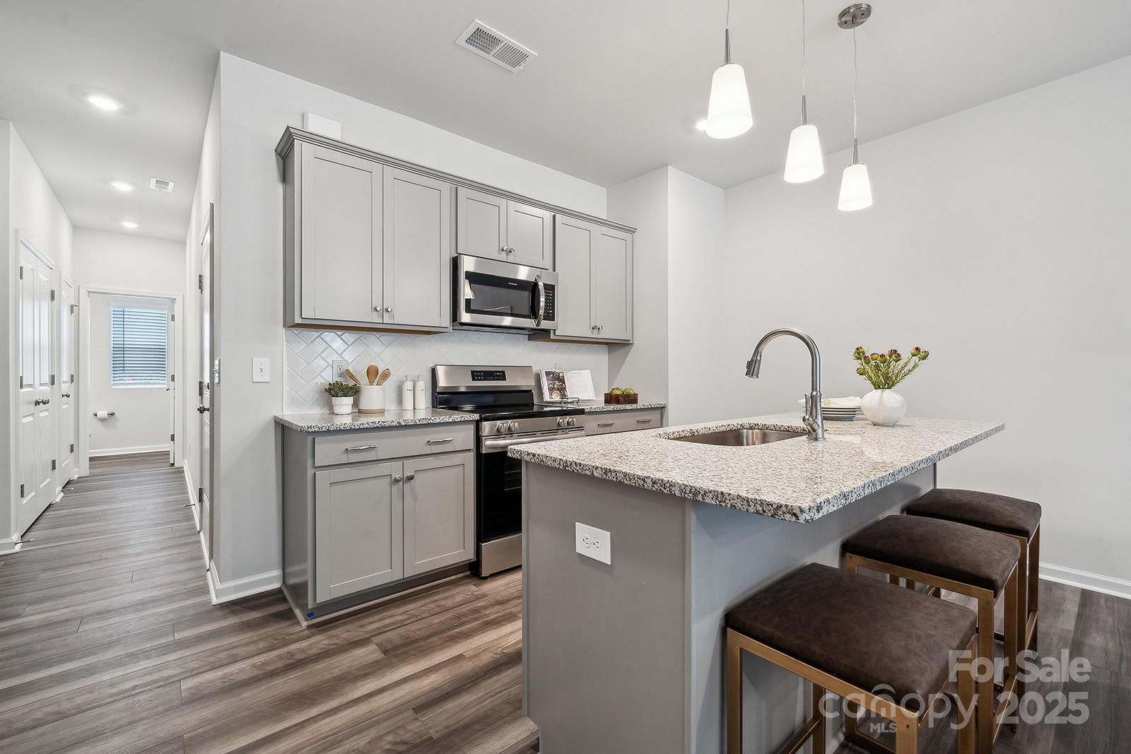 4738 Lakeview Road, Unit 16 Charlotte, NC 28216 - Photo 11 of 24 a kitchen with kitchen island granite countertop a sink cabinets and stainless steel appliances