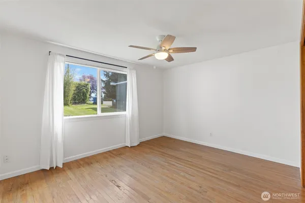 a view of empty room with wooden floor and fan