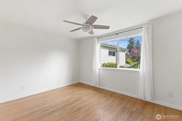 a view of empty room with wooden floor and fan