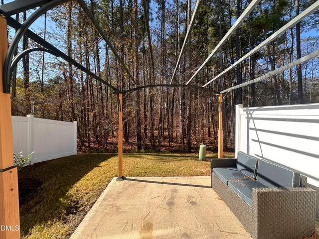 a view of a patio with a table and chairs and wooden fence