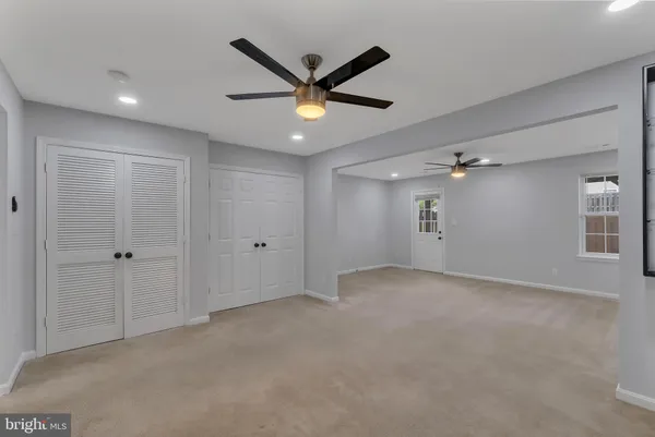 a view of a livingroom with a ceiling fan & windows