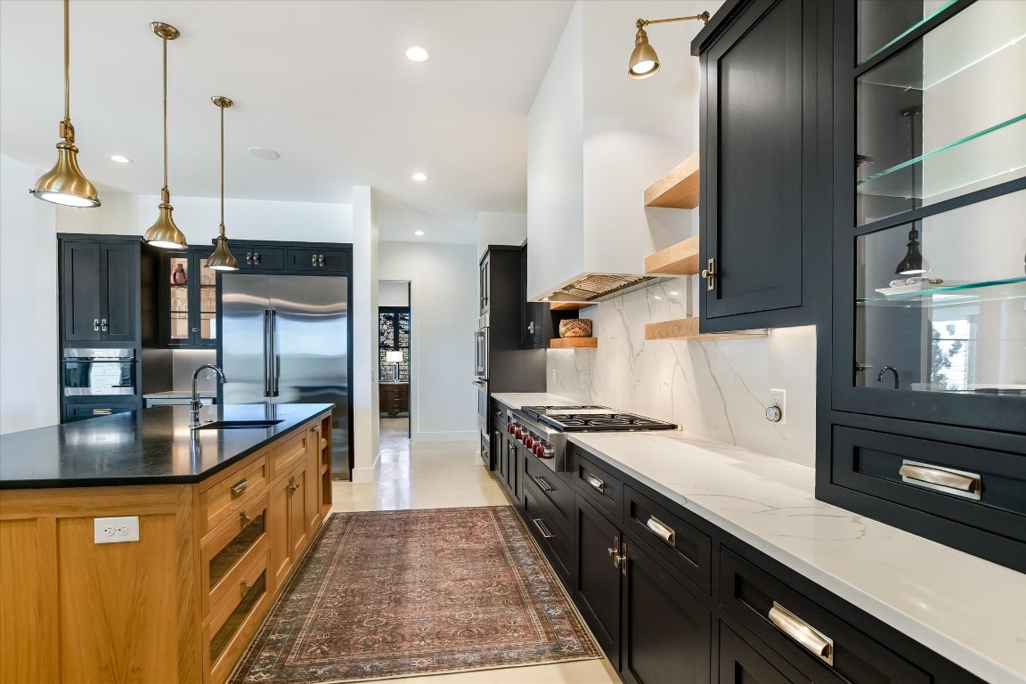 343 Pug Rippy Road Dripping Springs, TX 78620 - Photo 11 of 33 a kitchen with stainless steel appliances granite countertop a sink a counter top space cabinets and a wooden floor
